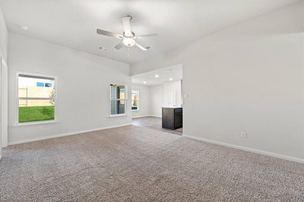 6308 Hyena Hollow Drive, Dallas, TX 75241 Unfurnished living room featuring ceiling fan, light colored carpet, and a healthy amount of sunlight