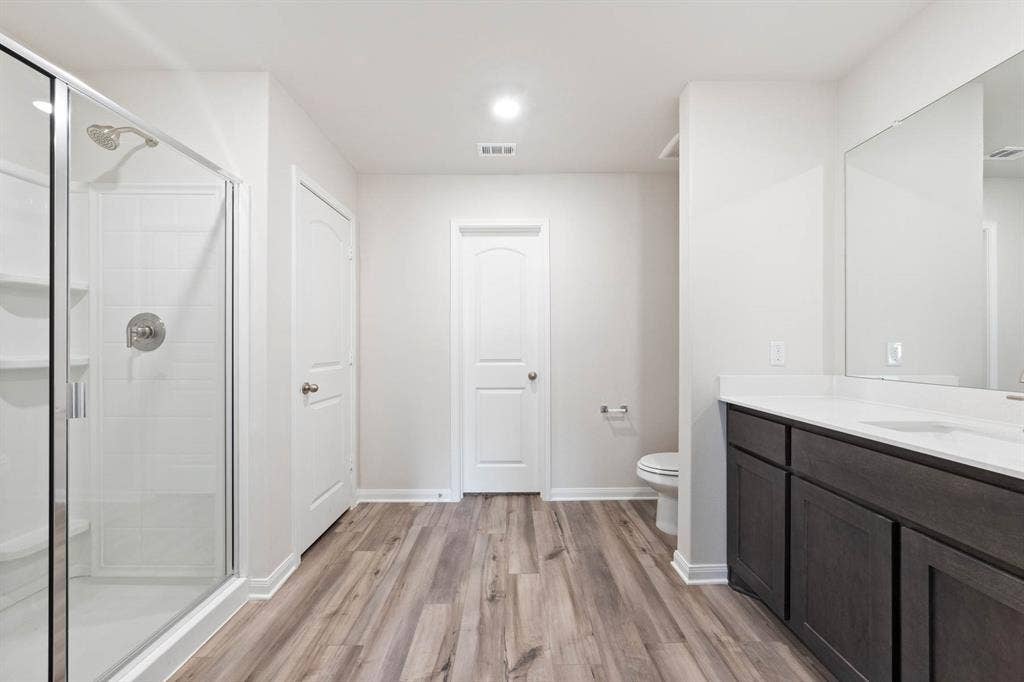 6308 Hyena Hollow Drive, Dallas, TX 75241 Bathroom with vanity, wood-type flooring, a shower with shower door, and toilet