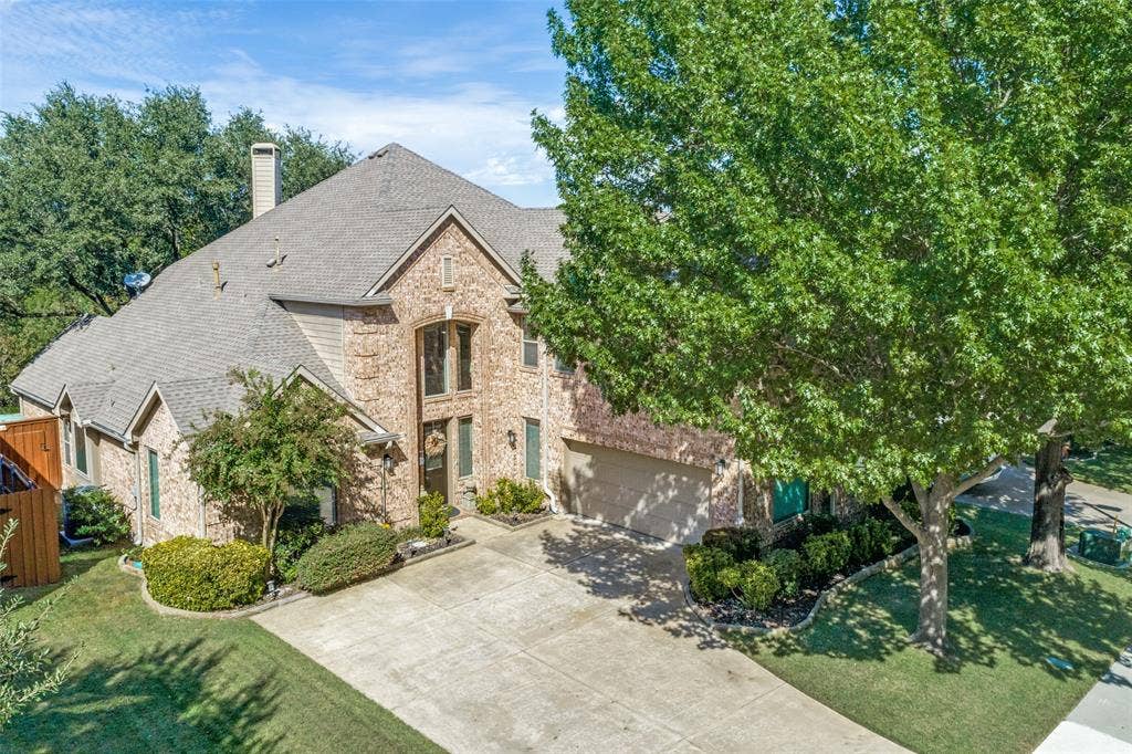 2404 Creek Ridge Drive, McKinney, TX 75072 Multi-story brick exterior featuring a multi-gabled roofline, an arched entryway, and an attached multi-car garage