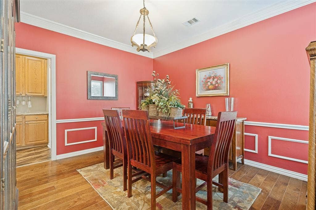 2404 Creek Ridge Drive, McKinney, TX 75072 Dining area featuring crown molding, custom wall wainscoting, wood-finish flooring, and a decorative pendant light fixture