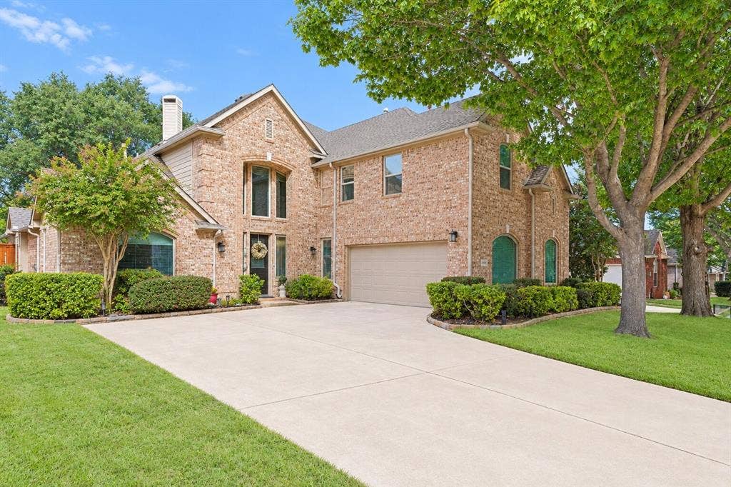 2404 Creek Ridge Drive, McKinney, TX 75072 Multi-story brick exterior featuring a multi-gabled roofline, an arched entryway, and an attached two-car garage