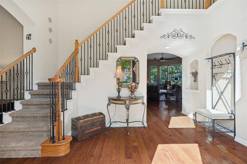 2404 Creek Ridge Drive, McKinney, TX 75072 Grand foyer featuring wood-finish flooring, a staircase with a wooden handrail, decorative iron balusters, and a recessed arched wall niche