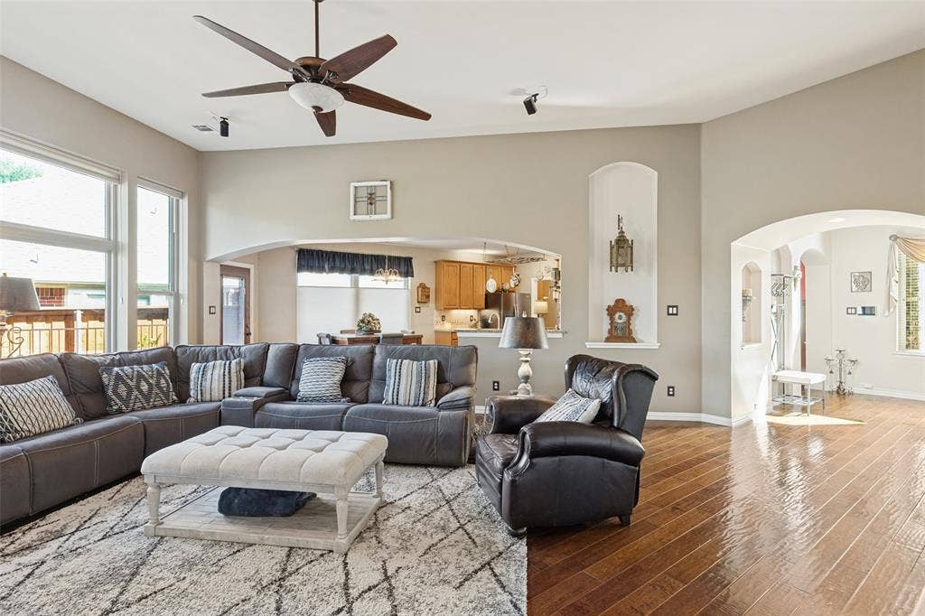 2404 Creek Ridge Drive, McKinney, TX 75072 Vaulted ceilings with a multi-blade ceiling fan, expansive wood-finish flooring, arched architectural detailing, and recessed wall niches