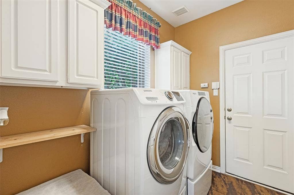 2404 Creek Ridge Drive, McKinney, TX 75072 Laundry room featuring white shaker-style wall cabinets, a natural wood floating shelf, and wood-finish flooring