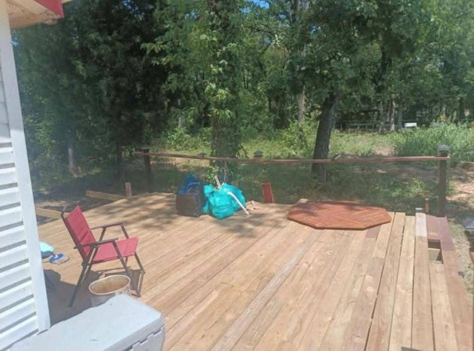 Wood-plank exterior deck featuring a simple rail system and mature trees