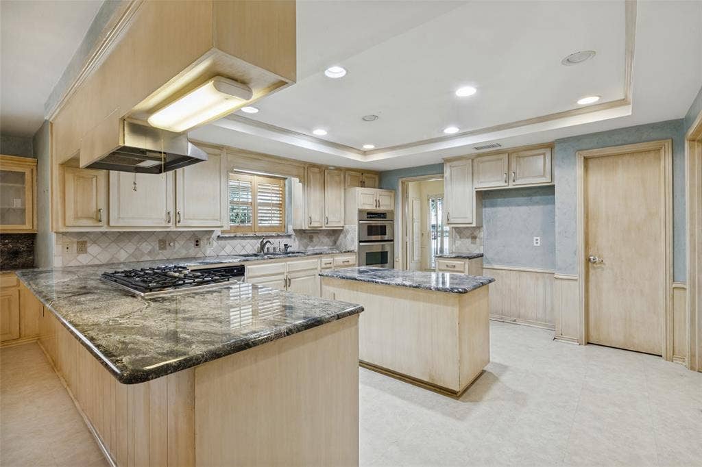 6936 Wildglen Drive, Dallas, TX 75230 Kitchen featuring light wood-finish cabinetry, kitchen island, granite countertops, convection oven and microwave, a gas cooktop and recessed ceiling lighting