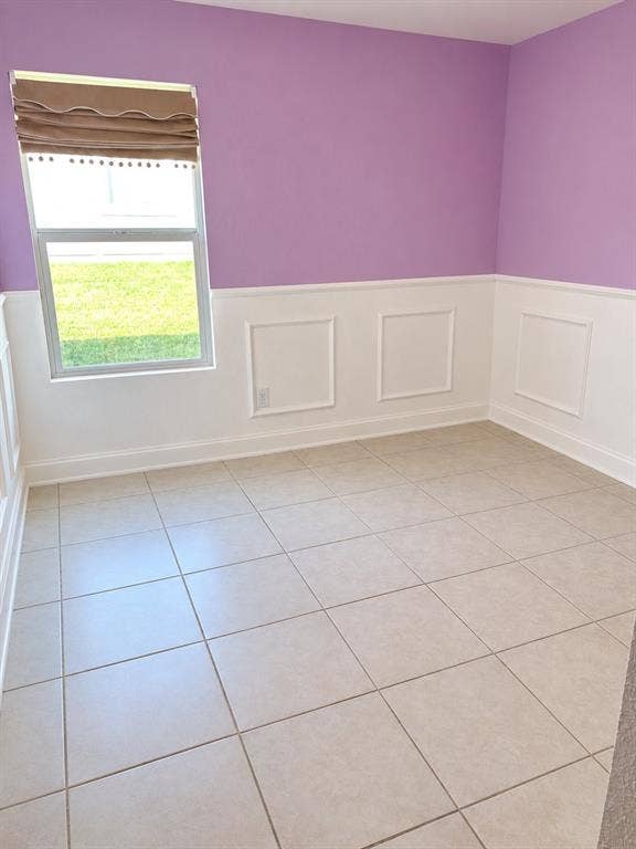 Interior space featuring large-format tile flooring, crisp white wainscoting with classic picture-frame molding, and a single-hung window