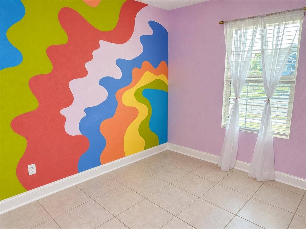Neutral tile flooring and a multi-colored abstract wall mural