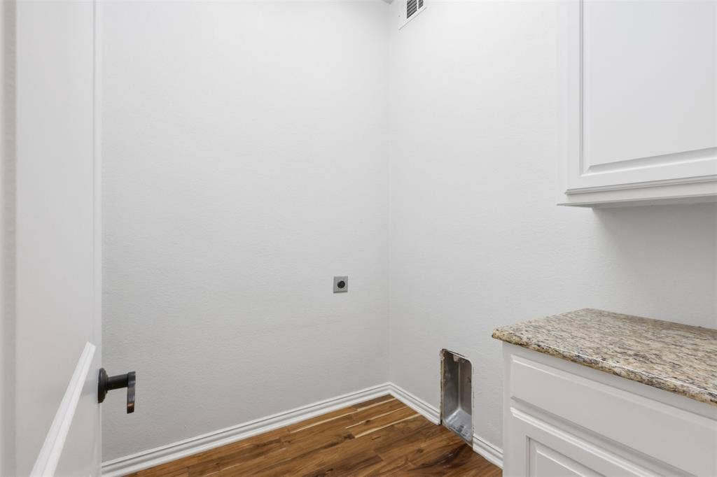 Utility area featuring wood-finish flooring, stone-surfaced countertop, built-in white cabinetry, and matte black hardware