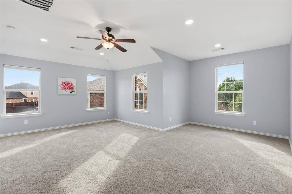 Spacious room featuring a vaulted ceiling, recessed lighting, neutral carpeting, and a multi-blade ceiling fan