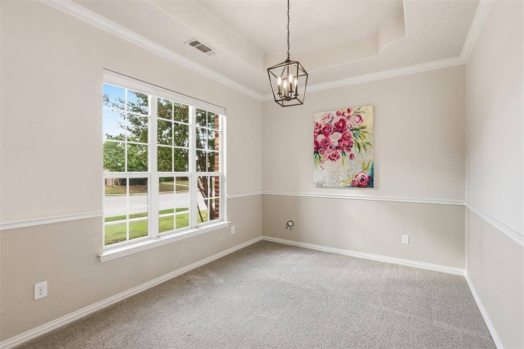 Tray ceiling, geometric metal pendant light, multi-pane window with grid pattern, and chair rail molding