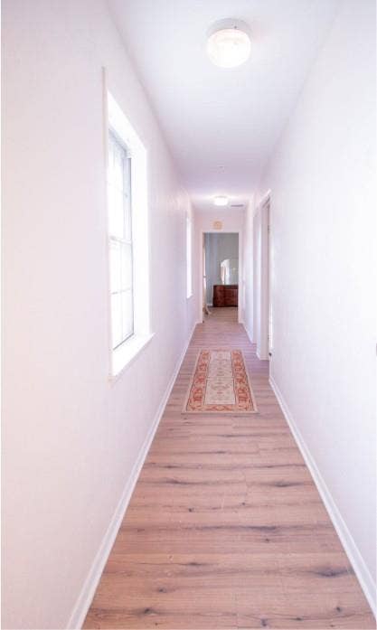 Hallway featuring wood-finish flooring, two vertical windows with white framing, and dual flush-mount ceiling light fixtures