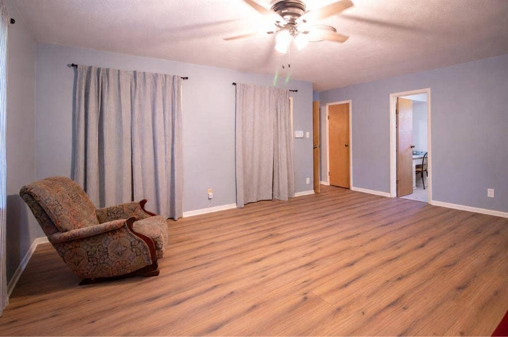 Interior room featuring wood-finish flooring, a ceiling-mounted light fixture with a fan, and solid-core interior doors
