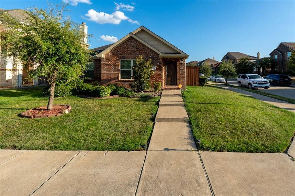 Single-story residence featuring a classic brick exterior, gabled roofline, concrete walkway, and landscaped front lawn