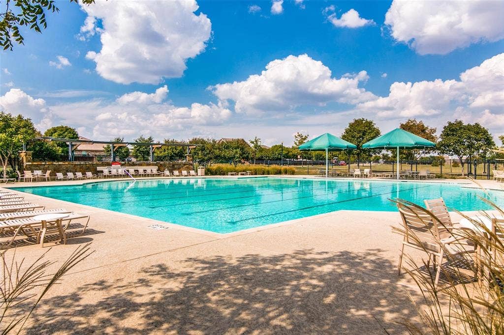 Large swimming pool featuring lap lanes, aggregate concrete decking, and integrated shade structures