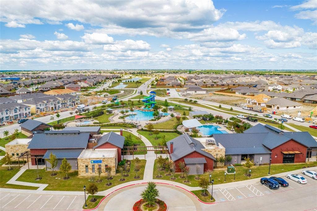 Community recreation center featuring multiple swimming pools, a water slide, landscaped grounds, and dedicated parking