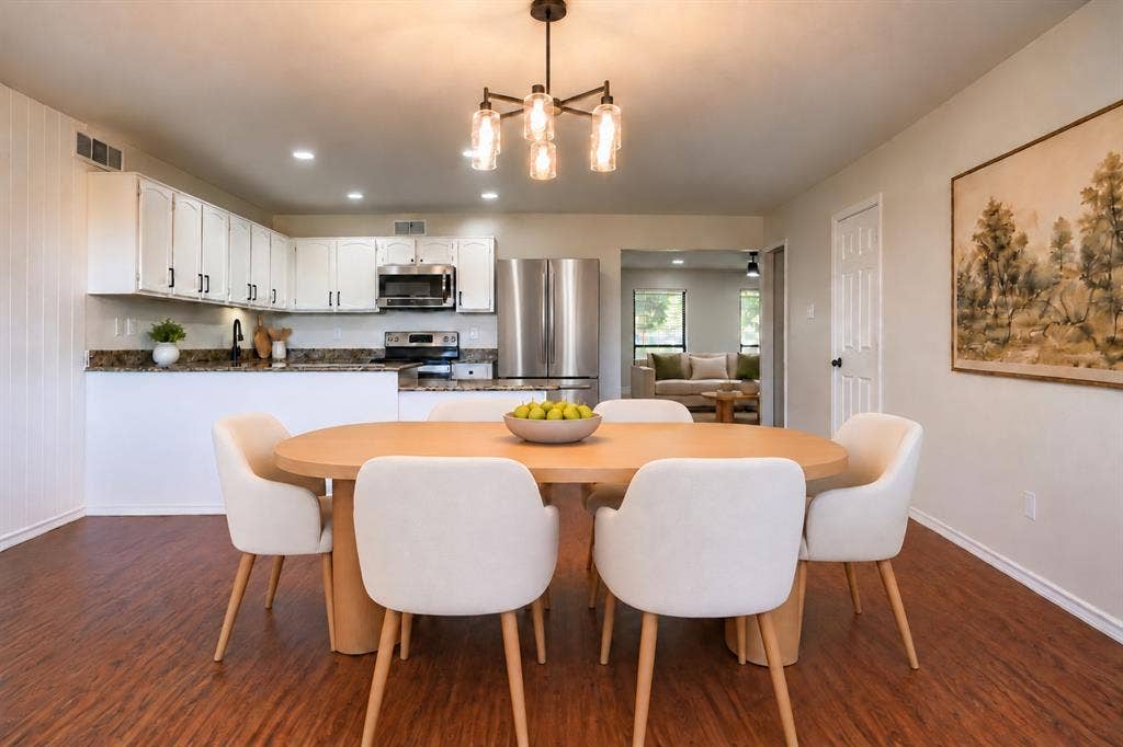 Kitchen featuring white cabinetry, stone-finish countertops, stainless steel appliances, wood-finish flooring, and a multi-arm chandelier