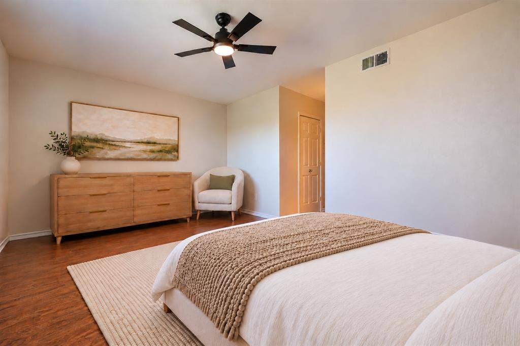 Wood-finish flooring, ceiling fan with integrated lighting, and a paneled interior door
