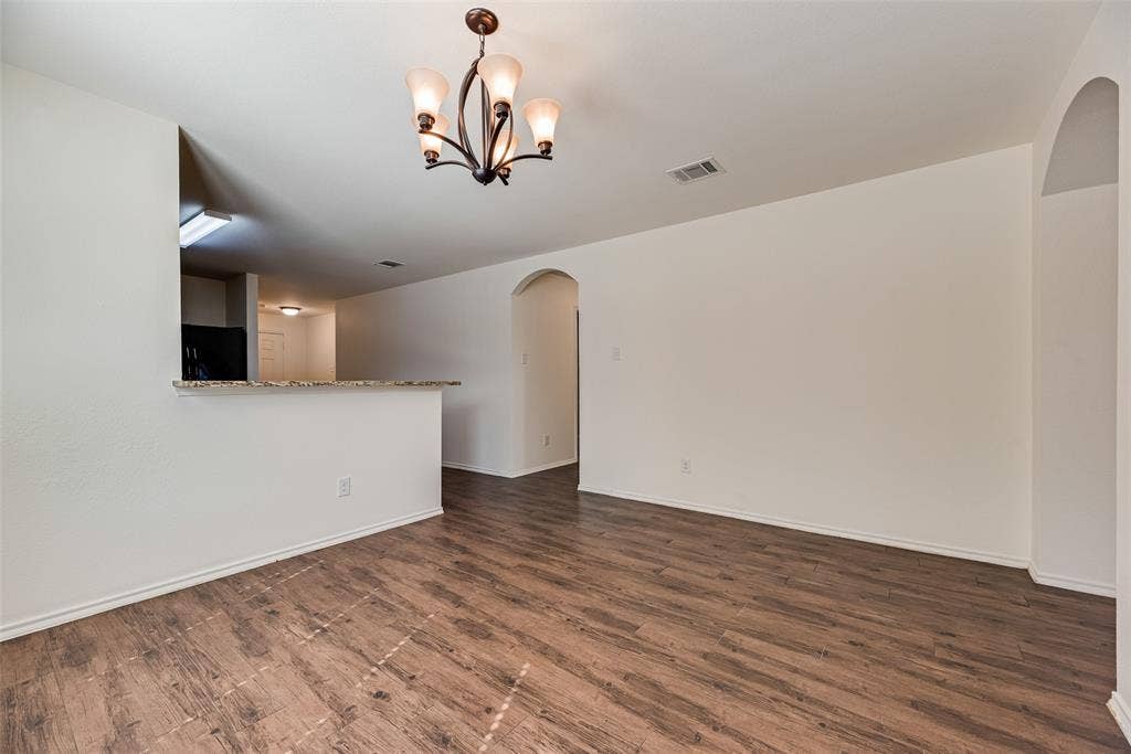 Wood-finish flooring, stone-surfaced breakfast bar, multi-arm chandelier, and arched doorways
