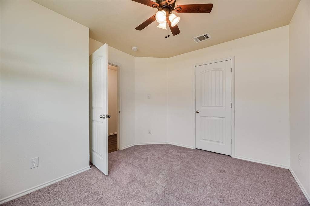Neutral interior space featuring wall-to-wall carpeting, an arched-panel interior door, and a multi-light ceiling fan