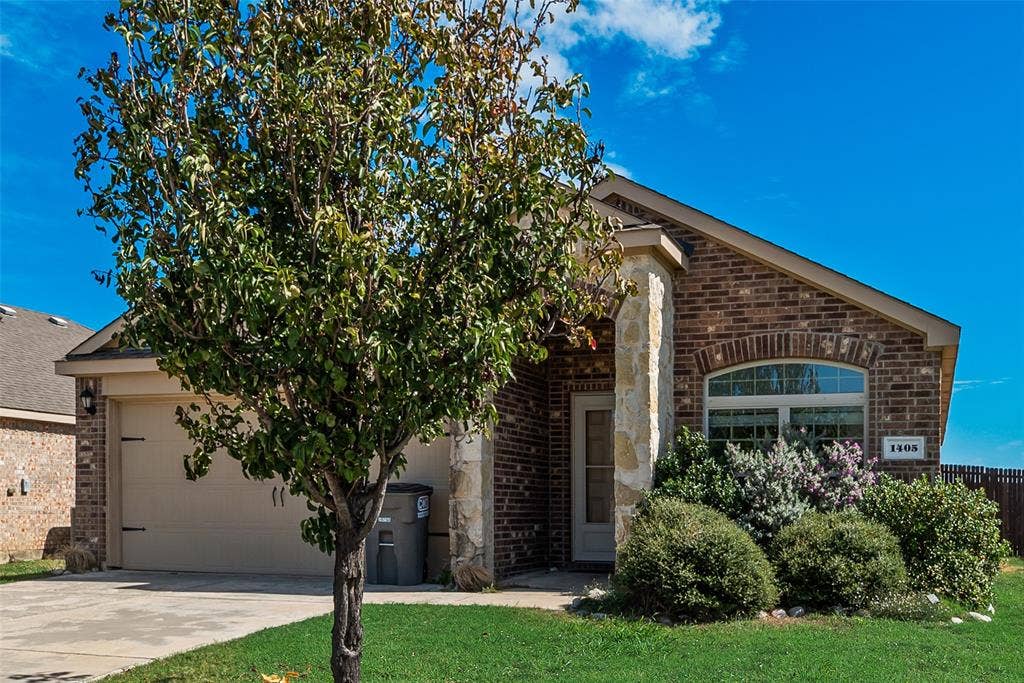 Brick exterior featuring natural stone accents, arched window detailing, and an attached two-car garage