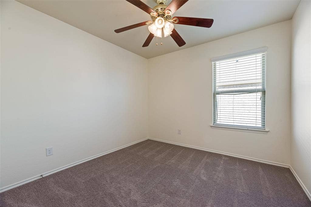 Room featuring neutral wall tones, carpeted flooring, a ceiling fan with integrated light fixture, and a window equipped with horizontal blinds