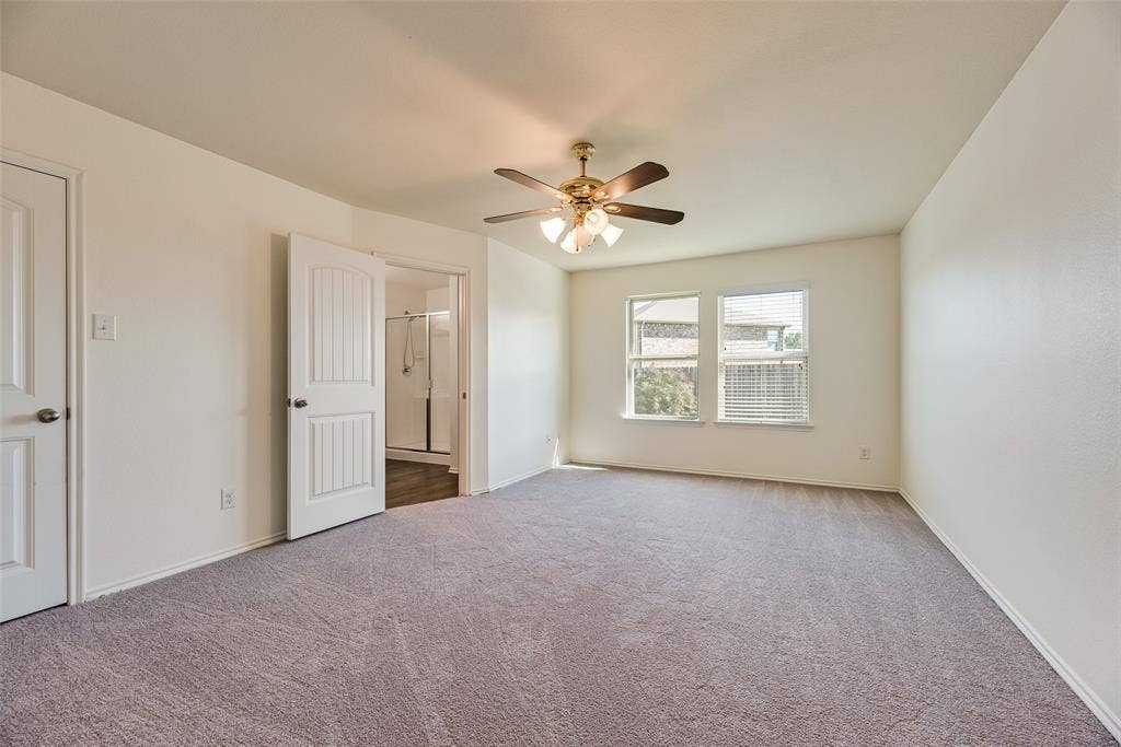Neutral-toned carpeted flooring, multi-panel interior doors, and a ceiling fan with integrated multi-bulb light fixture
