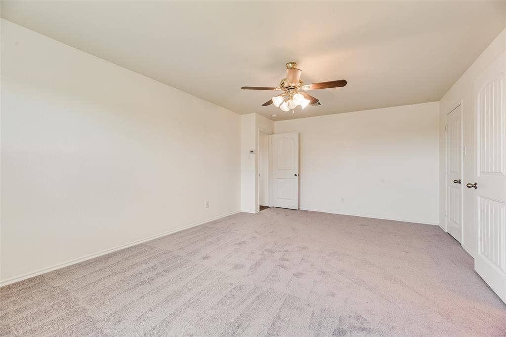 Neutral-toned wall-to-wall carpeting, multi-panel interior doors, and a ceiling-mounted light fixture with a fan