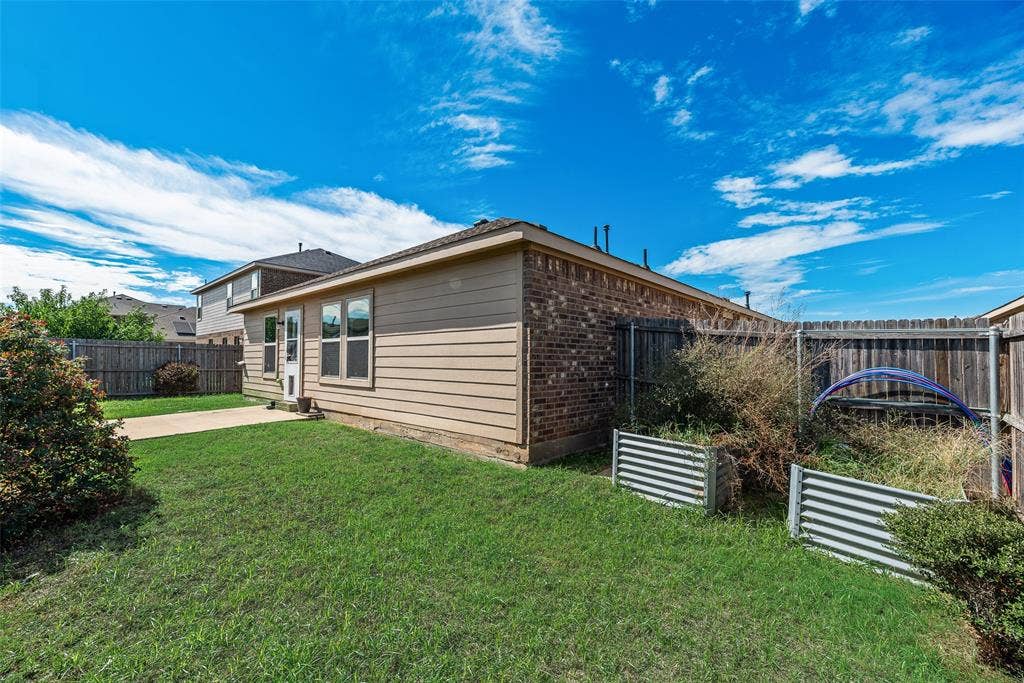 Rear exterior featuring a brick and horizontal siding facade, concrete patio, and fenced perimeter