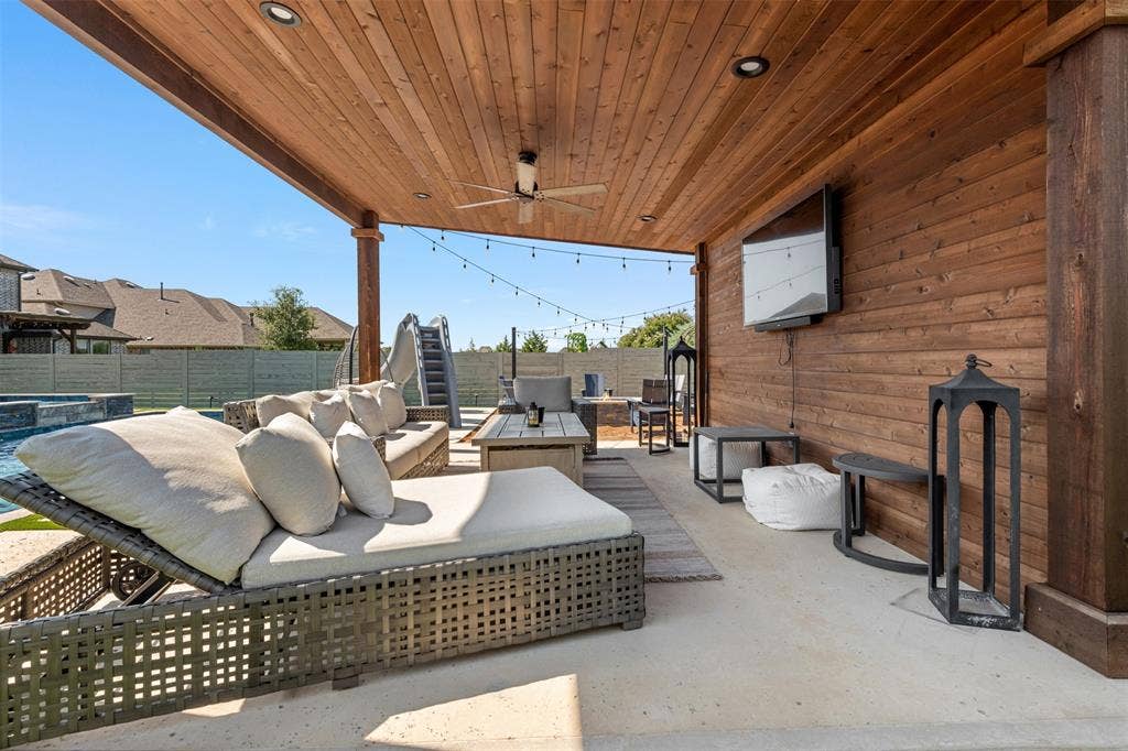 Covered patio featuring wood-paneled ceiling, recessed lighting, ceiling fan, and wall-mounted television