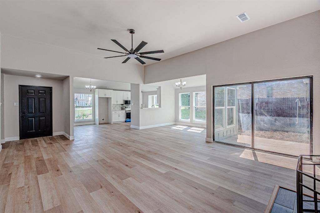 Vaulted ceiling, wood-finish flooring, multi-blade ceiling fan, sliding glass door, and recessed lighting