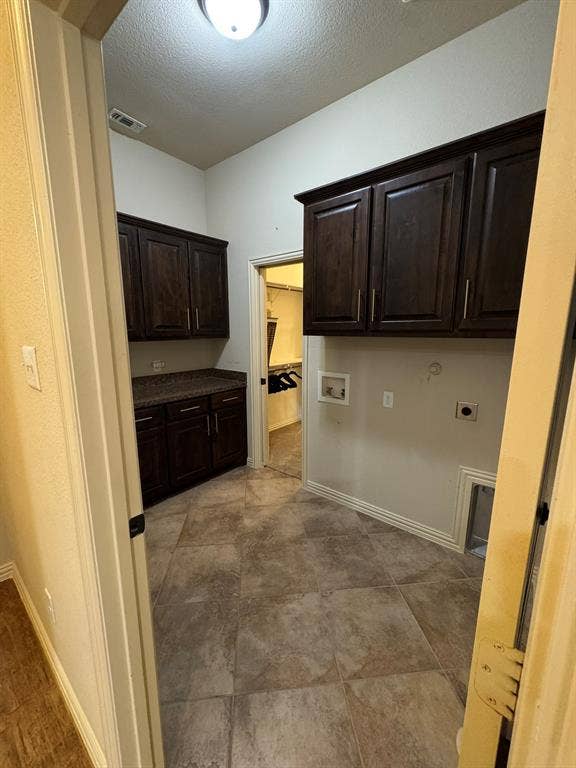 3953 Hollow Lake Road, Fort Worth, TX 76262 Utility room featuring dark-finish cabinetry, stone-texture countertops, tile flooring, and wall-mounted storage units
