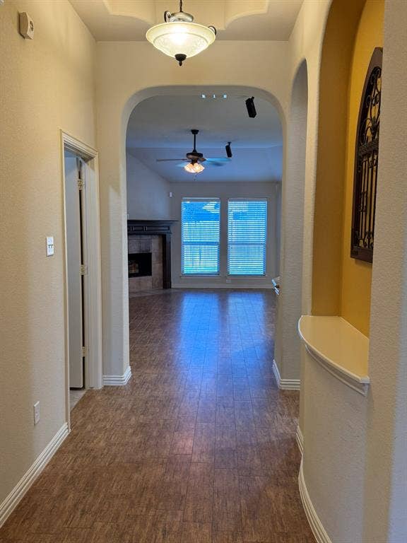 3953 Hollow Lake Road, Fort Worth, TX 76262 Entryway featuring wood-finish flooring, an arched architectural alcove with a built-in display shelf, a recessed ceiling tray, and a semi-flush mount light fixture