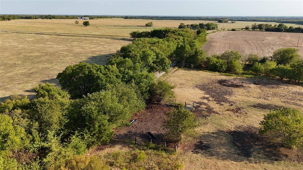 Expansive acreage featuring mature trees, cleared pasture land, and fenced enclosures