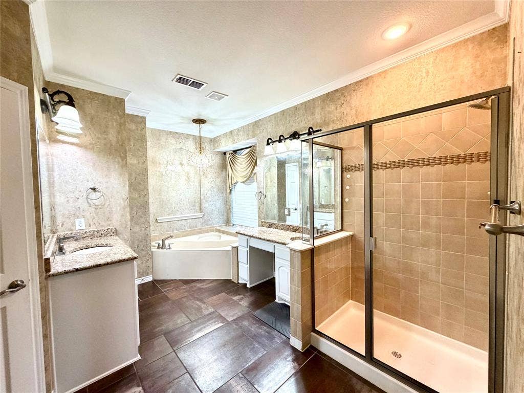 4514 Sea Sparrow Lane, Garland, TX 75043 Bathroom featuring tile flooring, a walk-in shower with glass enclosure, corner soaking tub, dual-sink vanity with stone countertop, and crown molding