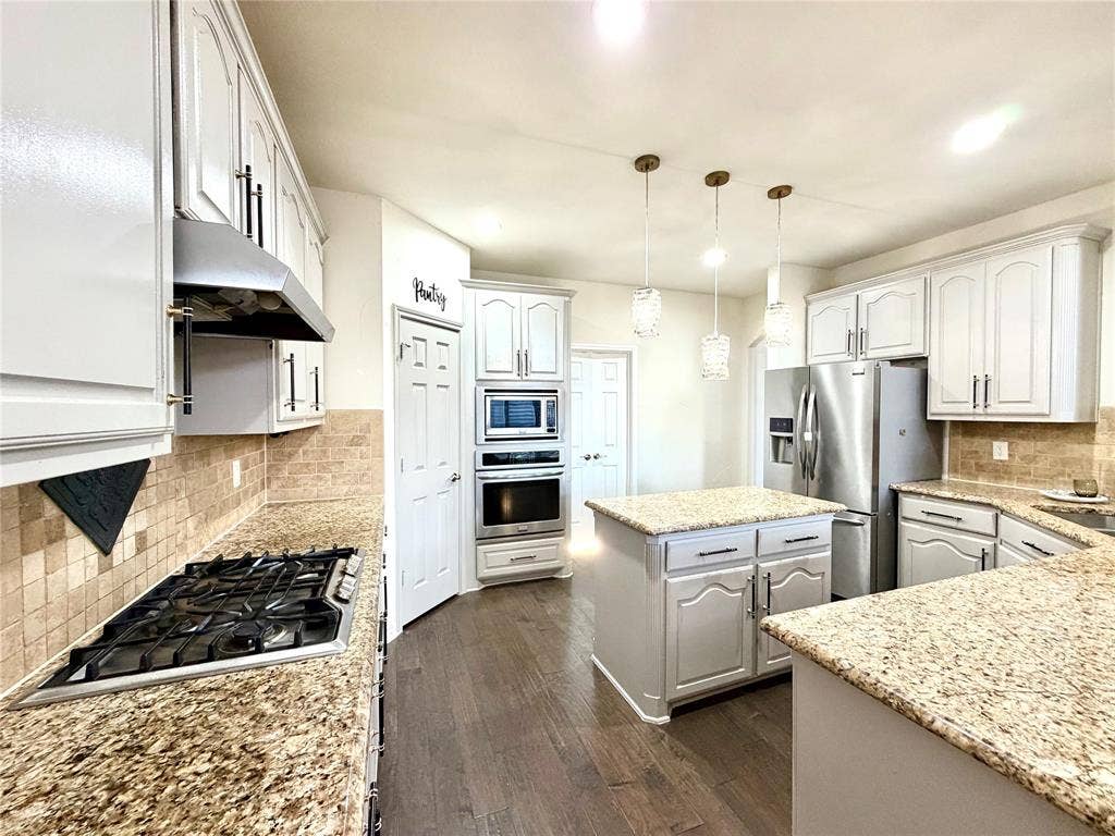 4514 Sea Sparrow Lane, Garland, TX 75043 Kitchen featuring stone countertops, white cabinetry, wood-finish flooring, stainless steel built-in appliances, and pendant lighting