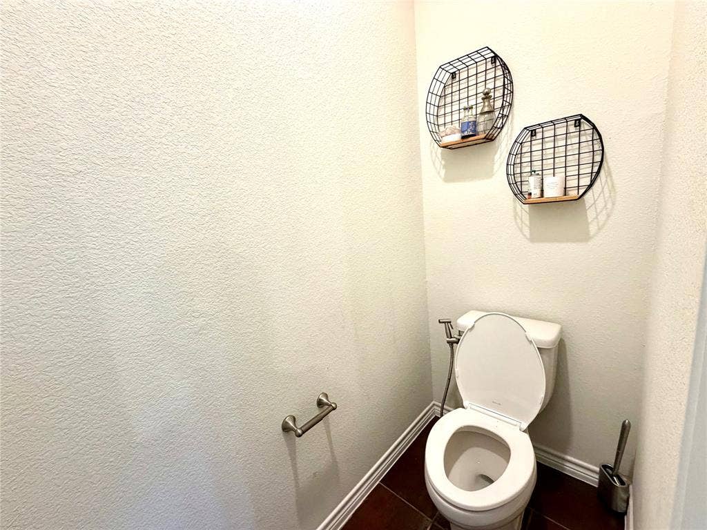 4514 Sea Sparrow Lane, Garland, TX 75043 Restroom featuring dark ceramic tile flooring and a dual-flush toilet with an integrated bidet sprayer