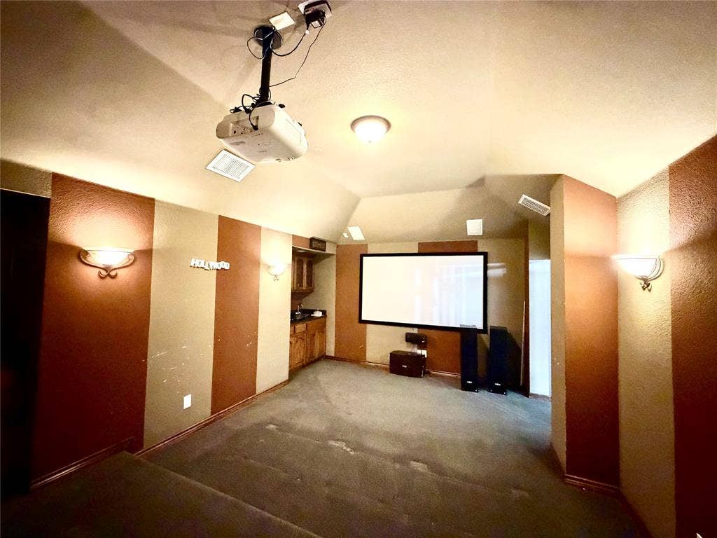4514 Sea Sparrow Lane, Garland, TX 75043 Media room featuring tiered flooring, a ceiling-mounted projector, wall-mounted light fixtures, and built-in cabinetry with a countertop