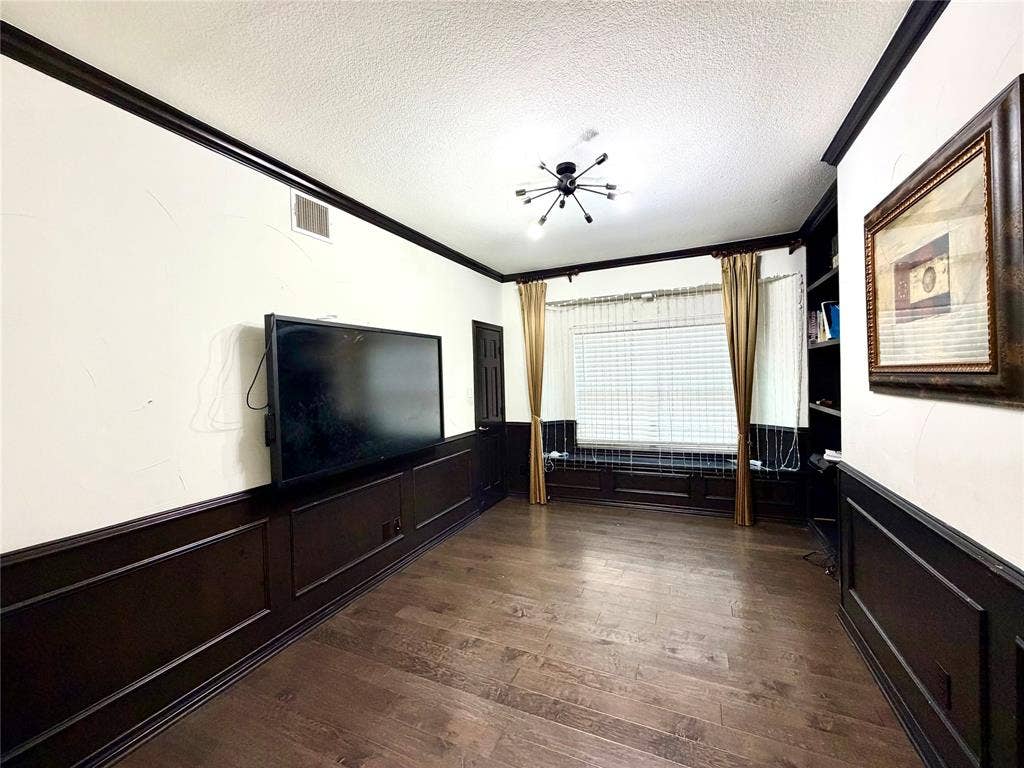 4514 Sea Sparrow Lane, Garland, TX 75043 Room featuring wood-finish flooring, dark wainscoting, built-in shelving, a bay window with a window seat, and a modern sputnik-style chandelier