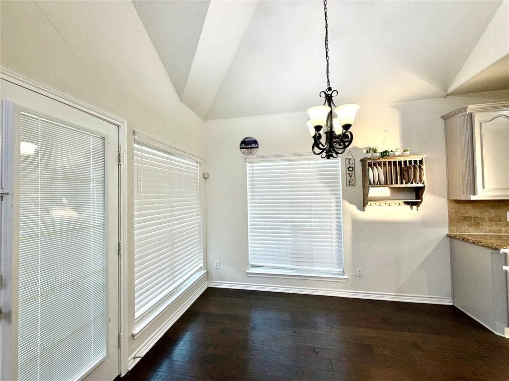 4514 Sea Sparrow Lane, Garland, TX 75043 Vaulted ceiling, dark wood-finish flooring, multi-light iron chandelier, built-in wooden wall shelving, and a full-lite glass door