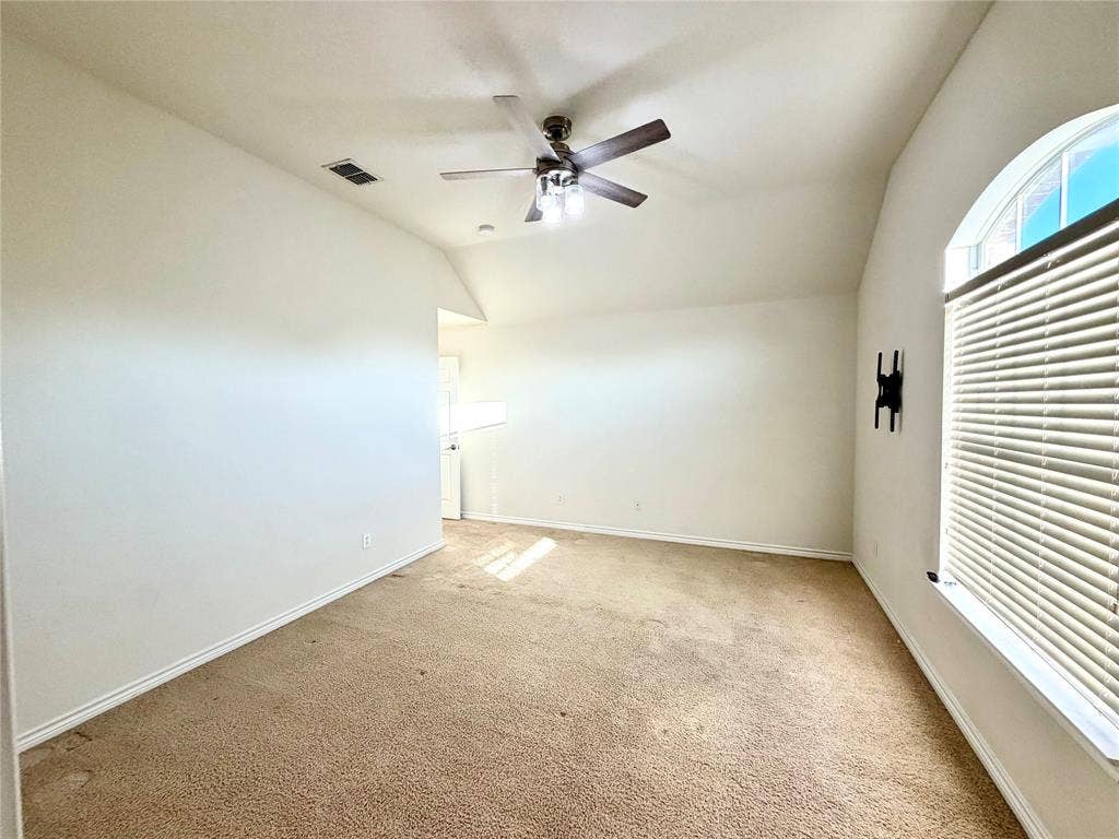 4514 Sea Sparrow Lane, Garland, TX 75043 Vaulted ceiling featuring a central light-integrated ceiling fan and an arched window with horizontal blinds