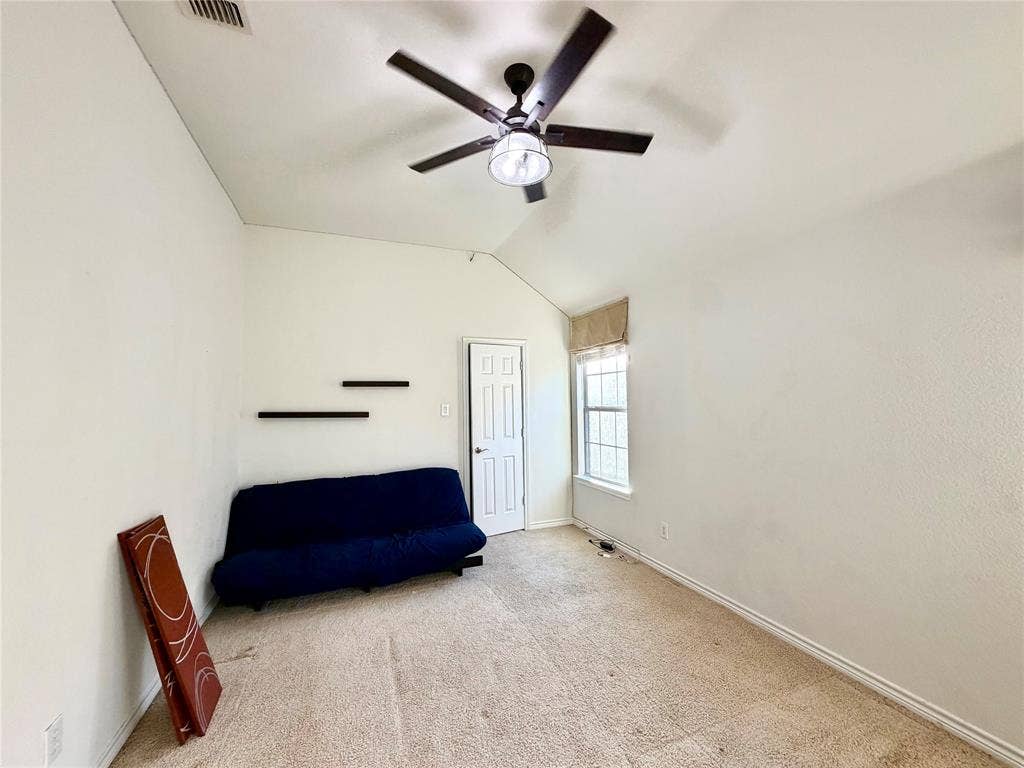 4514 Sea Sparrow Lane, Garland, TX 75043 Vaulted ceiling featuring a central five-blade ceiling fan with integrated lighting, wall-mounted floating shelving, and a single-pane window with grid detailing