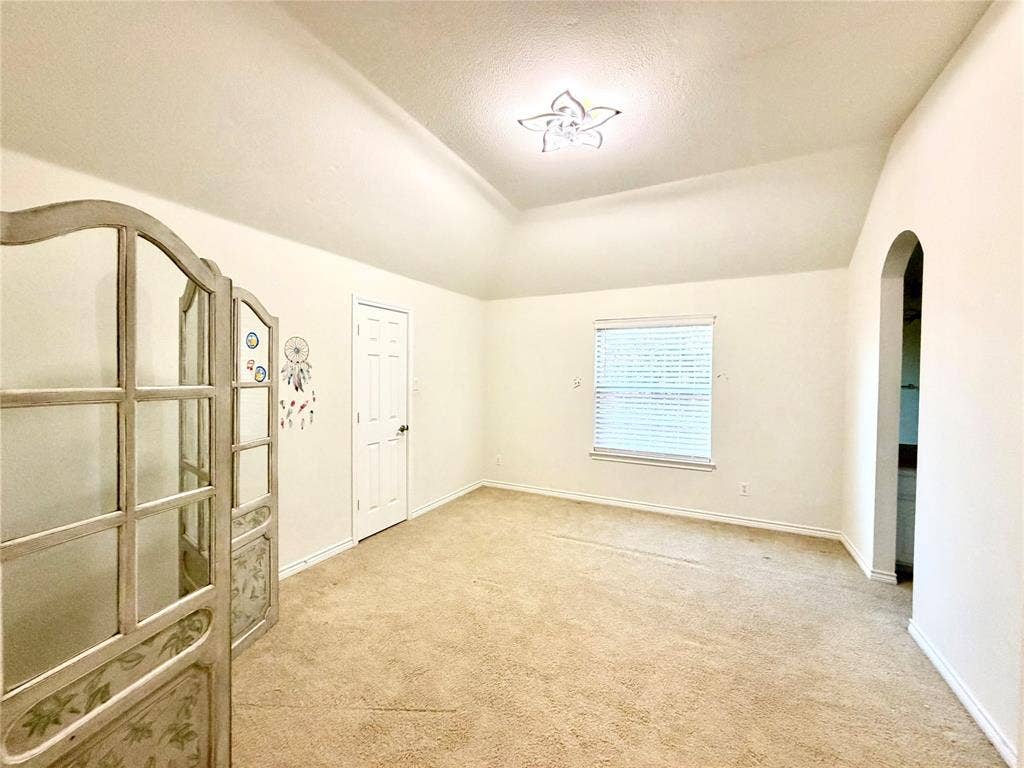 4514 Sea Sparrow Lane, Garland, TX 75043 Vaulted ceiling featuring a decorative floral-style ceiling light fixture, neutral wall-to-wall carpeting, and an arched entryway