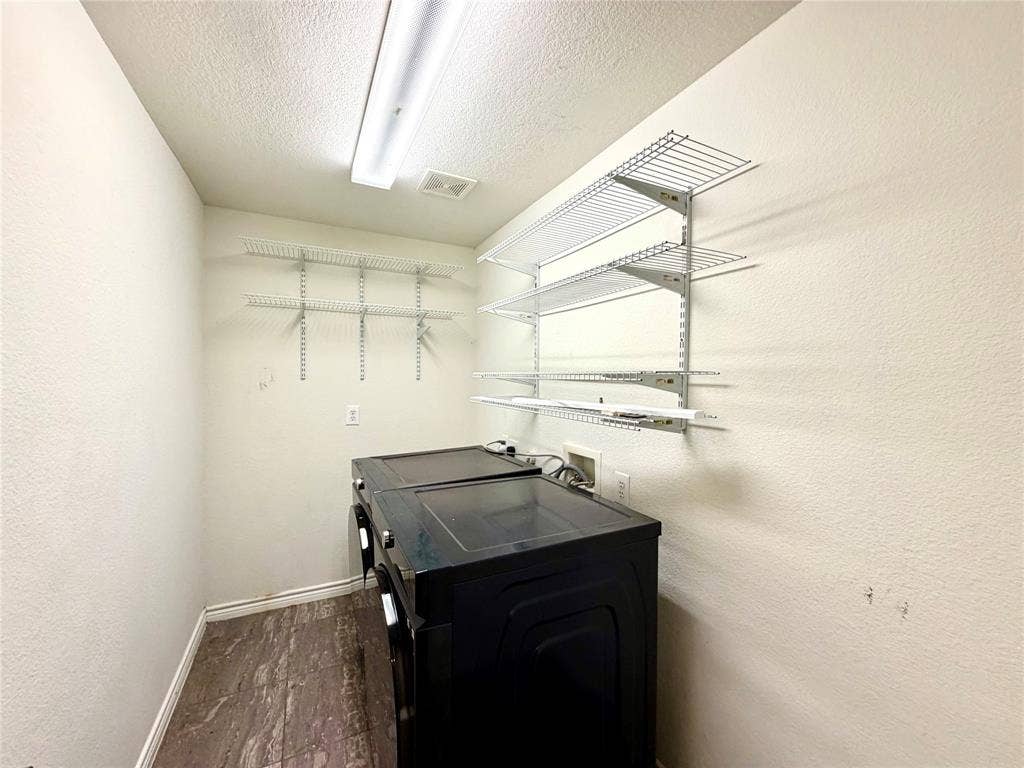 4514 Sea Sparrow Lane, Garland, TX 75043 Utility space featuring wood-finish flooring, white wall-mounted wire shelving, and linear flush-mount overhead lighting