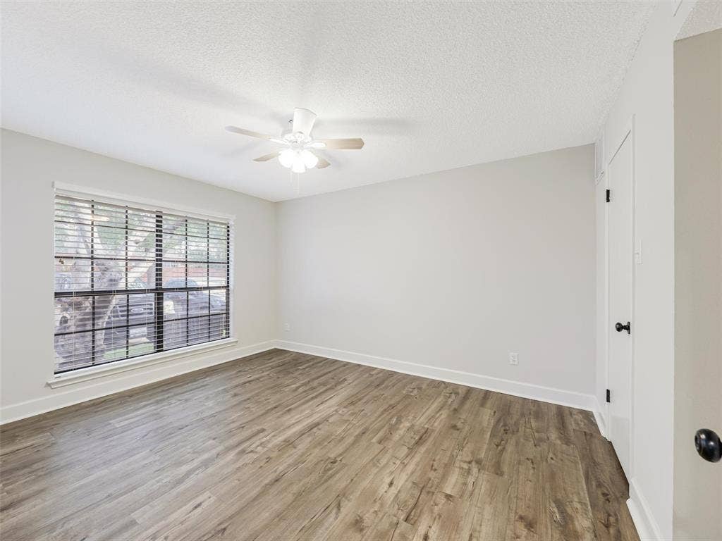 449 Harris Street, #102L, Coppell, TX 75019 Room featuring wood-finish flooring, a neutral color palette, a ceiling fan with integrated lighting, and a multi-pane window with horizontal blinds