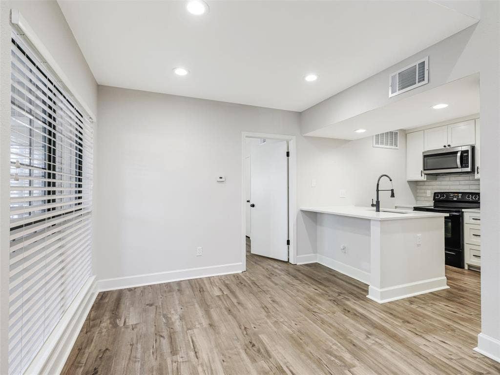 449 Harris Street, #102L, Coppell, TX 75019 Wood-finish flooring, recessed lighting, white cabinetry, matte black hardware, and a breakfast bar