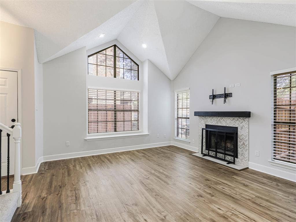 449 Harris Street, #102L, Coppell, TX 75019 Vaulted ceilings featuring recessed lighting, expansive triangular accent window, fireplace with herringbone tile surround and wood-finish mantel, and wood-finish flooring