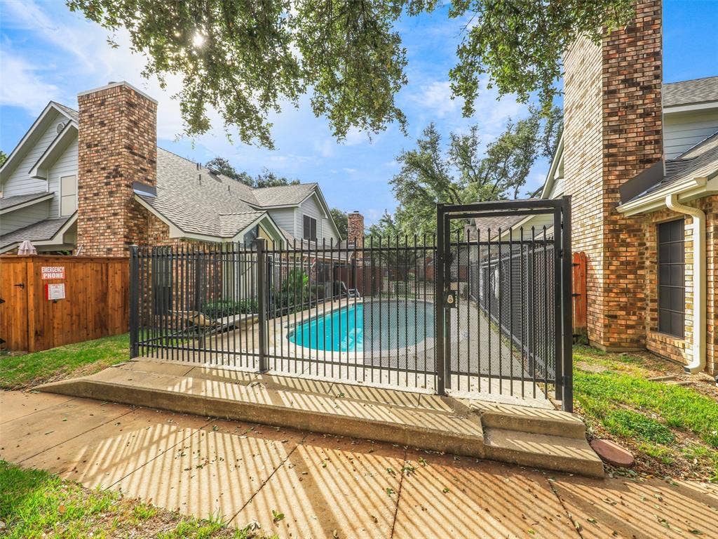 449 Harris Street, #102L, Coppell, TX 75019 Fenced pool area featuring a concrete deck, brick chimneys, and partial wood privacy fencing