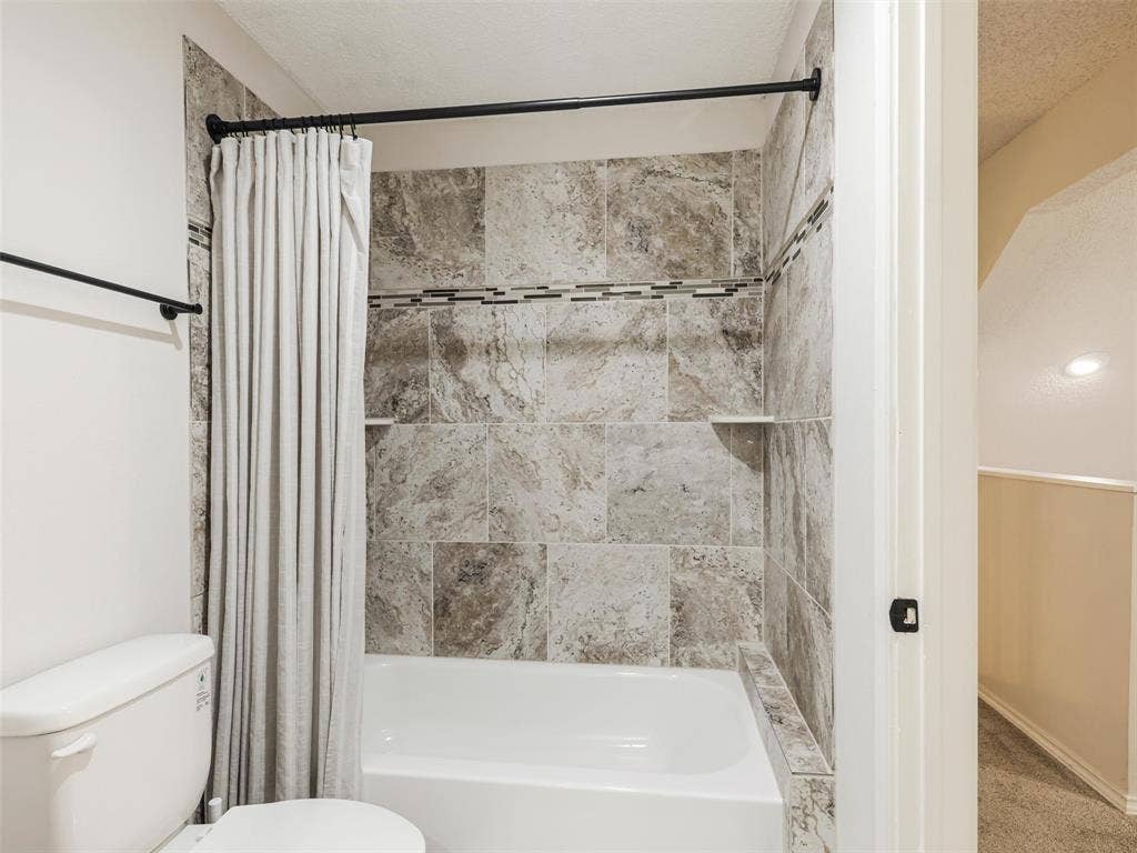449 Harris Street, #102L, Coppell, TX 75019 Full-size bathtub with patterned tile surround, integrated recessed shelving, and a decorative mosaic accent border