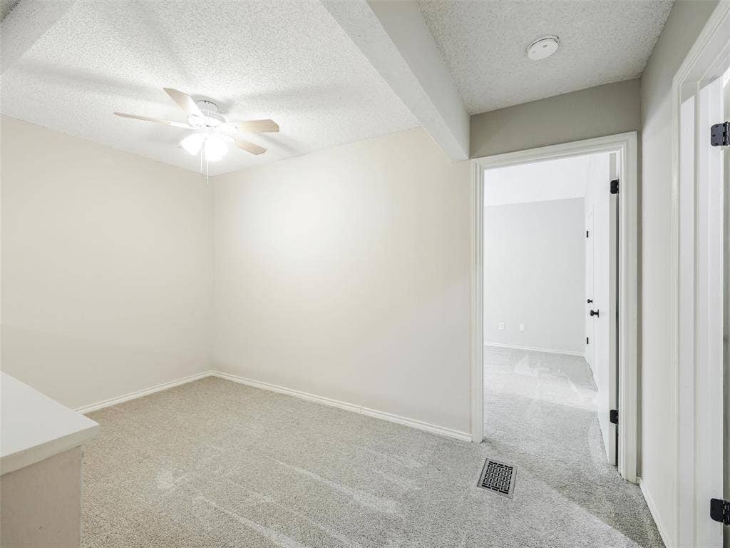 449 Harris Street, #102L, Coppell, TX 75019 Neutral-toned interior space featuring wall-to-wall carpeting, a ceiling fan with integrated lighting, and a doorway with a hollow-core door